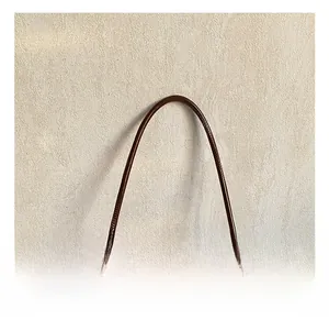 Close-up of slim brown leather handle with premium gold-tone metal hardware connectors