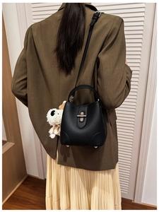 Close-up of black lychee grain bucket bag featuring silver buckle and plush dog charm