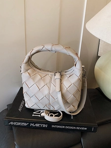 Sac à main beige tressé vintage avec bandoulière sur des livres de design de luxe