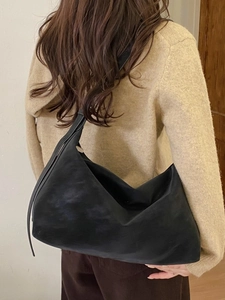 Minimalist large black hobo shoulder bag in soft leather shown on a female model