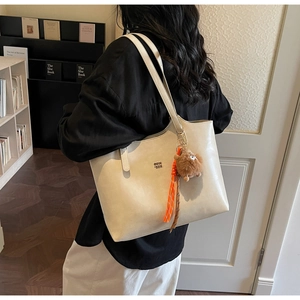 Détail d'un grand sac cabas crème avec ours en peluche marron et pompon orange vif