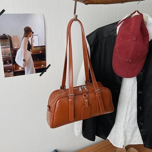 Detailed close-up of a vintage leather Boston bag in caramel brown with dual handles