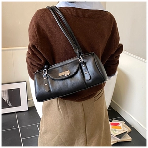 Detail of a black minimalist tote bag with silver metallic buckle on a female model