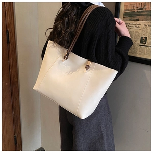 Side view of model wearing a large cream tote bag with brown straps for office commute