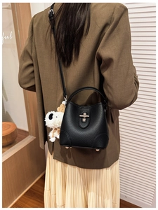 Black lychee leather bucket bag with silver clasp and a cute puppy plush charm pendant