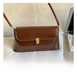 Close-up of the vintage gold hardware lock on a deep brown glossy leather baguette bag