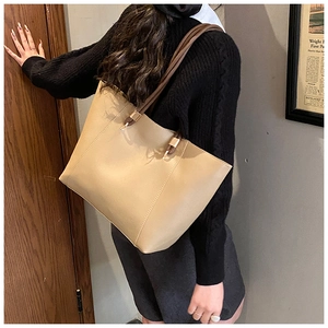 Detail view of large beige tote bag with brown PU leather straps and gold metal hardware