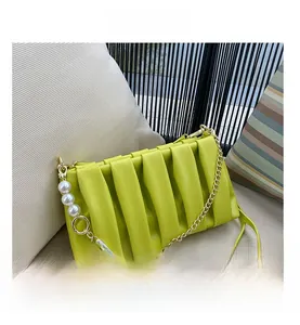 Detail of lime green pleated handbag with gold chain strap and pearl accents