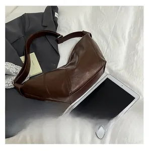 Macro view of textured brown leather croissant bag with adjustable strap and stitching