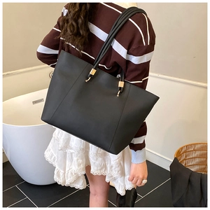 Detailed side view of a black leather tote bag featuring elegant golden metal buckles