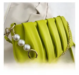 Detail showing the pleated faux leather texture, golden chain, and large pearl accents
