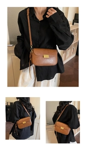 Detail of vintage brown shoulder bag showing gold metal buckle and smooth faux leather texture