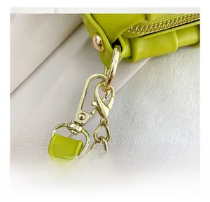 Detail of bright green leather bag side with polished gold detachable metal hook and chain