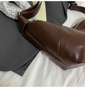 Detail of dark brown faux leather bag texture with silver zipper and wide strap