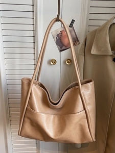 Borsa tote minimalista albicocca capiente in morbida pelle davanti a persiane bianche