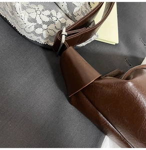 Close-up of brown textured leather bag strap with silver adjustable metal buckle detail
