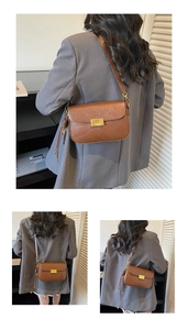 Detail of vintage brown leather crossbody bag featuring a golden square metal clasp