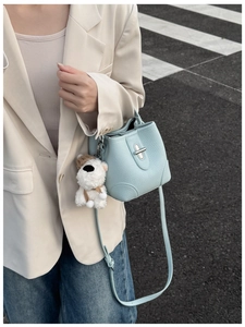 Detail of light blue lychee pattern bucket bag with silver clasp and puppy charm