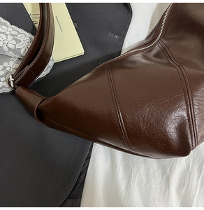 Close-up of a dark brown large hobo bag featuring glossy oil-wax leather and silver zipper