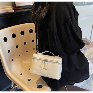 Détail du sac boîte crème montrant la texture cuir d'autruche et doubles zips