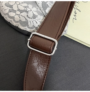Detail of brown leather strap with silver metal buckle and neat stitching on a lace background