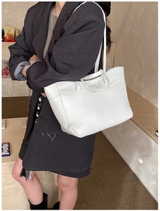 Close-up of a white leather tote bag with brand logo and durable dual-use handle straps