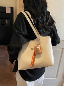 Minimalist beige leather tote bag with brown plush charm and shoulder strap