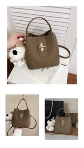 Detail of a brown leather bucket bag featuring a silver twist-lock and a cute puppy charm