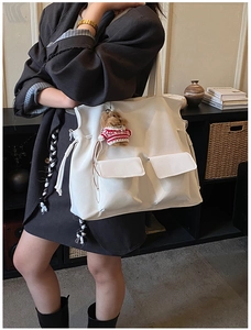 Detailed view of white large capacity tote bag featuring double pockets and bear charm