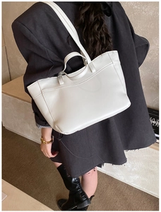 Close-up of a white leather tote bag with sturdy handles and a smooth textured finish