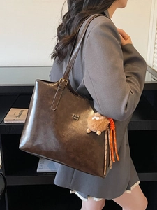 Large vintage dark brown leather tote bag with adjustable strap and plush pendant charm