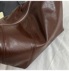 Macro detail of dark brown oil wax leather bag with vertical stitching and silver zipper