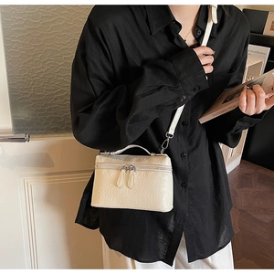 Détail d'un mini sac blanc à texture d'autruche avec double fermeture éclair sur mannequin