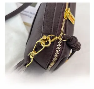 Detail of premium gold-tone lobster clasp and D-ring on dark brown leather boston bag