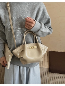 Nahaufnahme der beigefarbenen Plissee-Beuteltasche mit Goldverschluss und Schultergurt