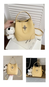 Detail of yellow bucket bag with lychee texture, metallic twist lock and plush puppy charm