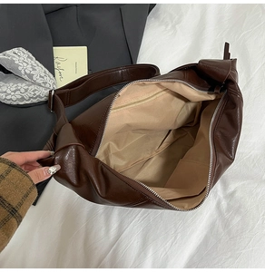 Close-up of brown pleated shoulder bag showing the zip closure and inner pockets