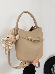 Minimalist beige pebble leather bucket bag with silver buckle and crochet rabbit charm
