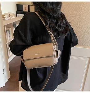 Detail of khaki lychee grain leather handbag with adjustable strap and side pouch