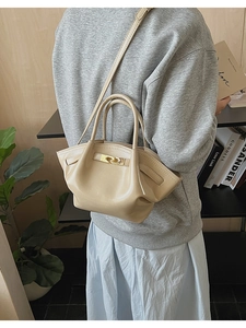 Detailansicht der beigen Faltenhandtasche aus Leder mit goldener Schließe am Schultergurt