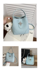 Close-up of light blue bucket bag with silver twist lock and cute white puppy charm