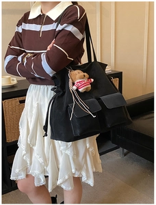 Vista lifestyle di una borsa tote nera con doppie tasche e ciondolo orsetto