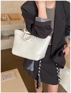 White minimalist tote bag styled with a gray suit in a chic cafe lifestyle setting