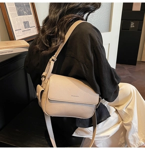 Close-up of beige pebble leather crossbody bag detail with side pocket and adjustable strap