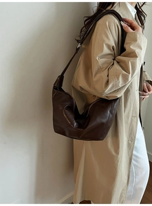 Detail of dark brown leather hobo bag with a polished finish and natural pleats