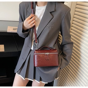 Détail de mini sac boîte bordeaux à texture autruche avec fermetures éclair argentées