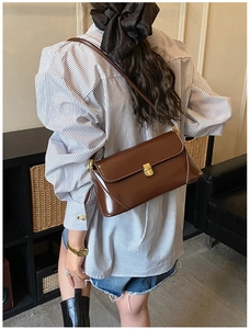 Close-up of a brown vintage leather baguette bag with a sleek gold rectangular clasp