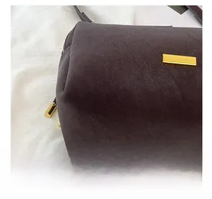 Detail of dark brown boston bag showing matte texture and golden rectangular buckle