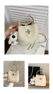 Detail of off-white lychee grain bucket bag with silver twist lock and plush puppy charm