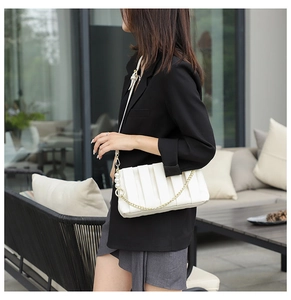 Detail of pleated crossbody bag featuring elegant pearl strap and gold chain accent